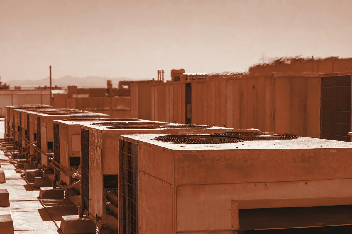 Rooftop HVAC condenser units under blazing summer sun with heat shimmer.